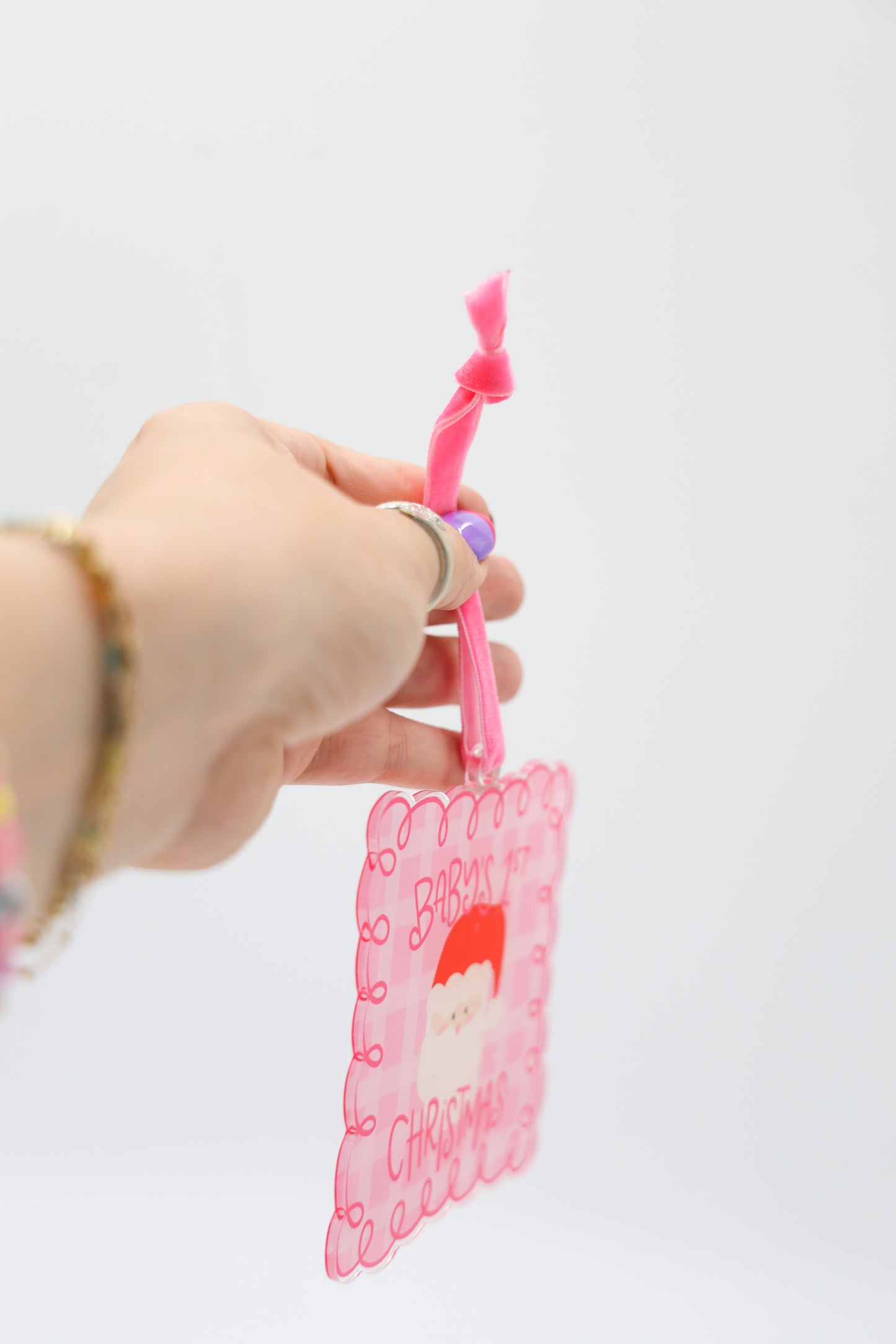 Hand holding a pink keychain with a Santa Claus design on a white background