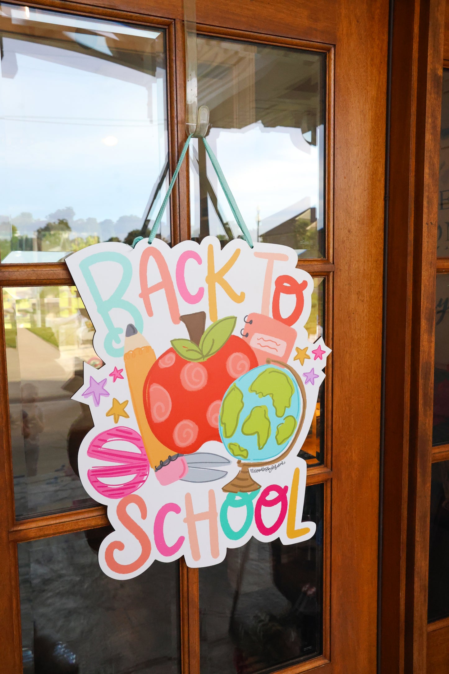 Colorful 'Back to School' sign hanging on a glass door.