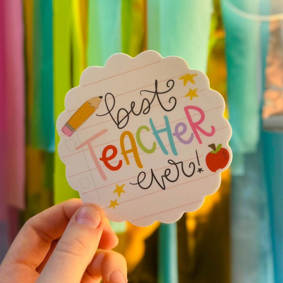 Doodles by Rebekah "Best Teacher Ever!" sticker with scalloped edges. This whimsical vinyl decal features hand-painted school-themed illustrations and colorful typography, making it an ideal teacher appreciation gift for laptops, planners, or water bottles.