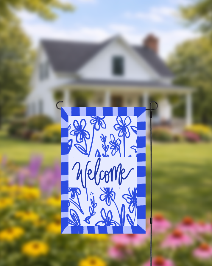 Garden flag with floral design and 'Welcome' text in front of a house with a garden.