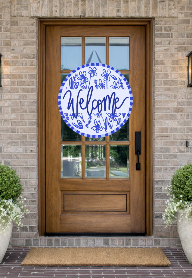 Doodles by Rebekah blue and white "Welcome" door decor featuring whimsical hand-painted floral illustrations and a striped border on a rustic front porch.