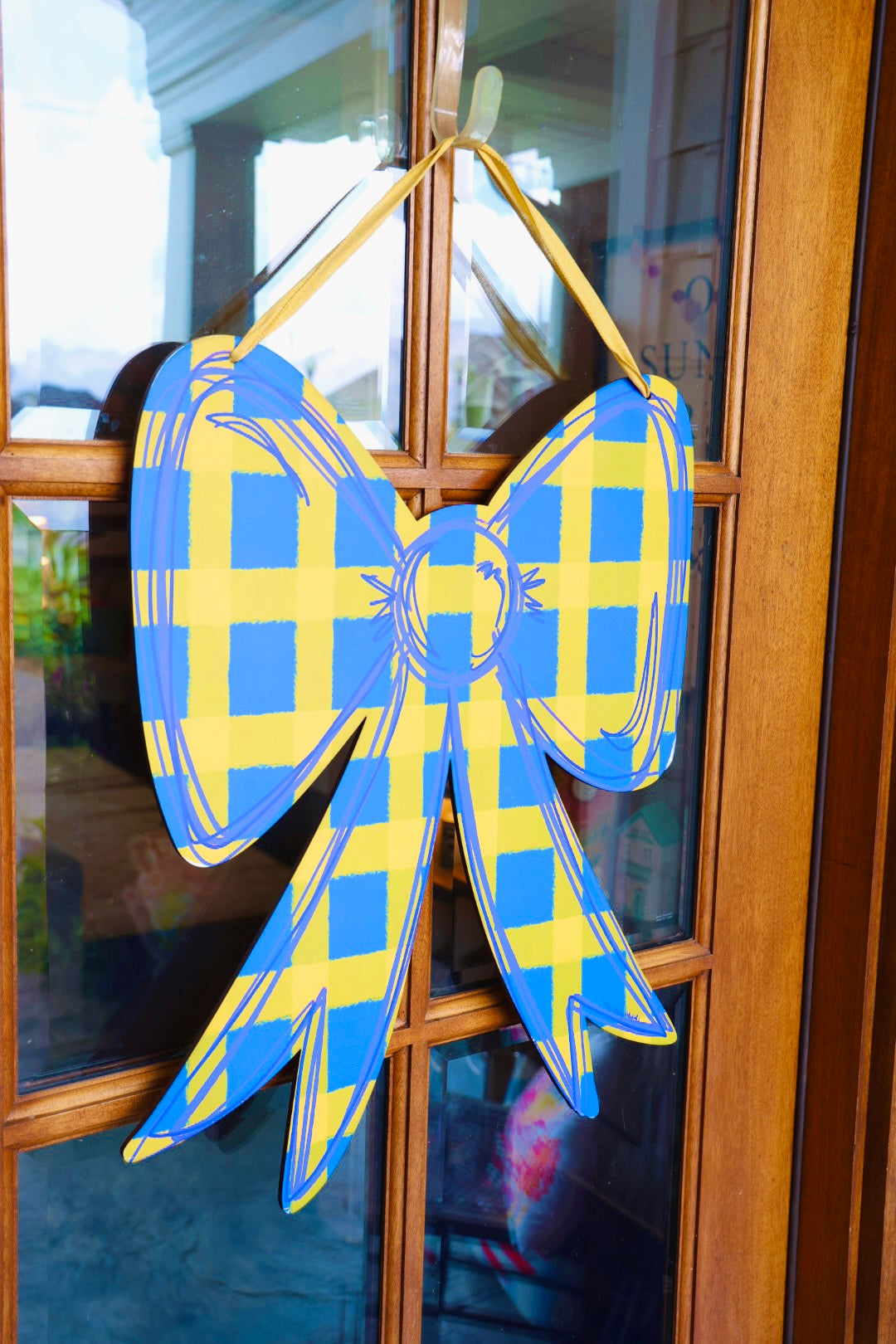Blue and yellow checkered bow decoration on a glass door