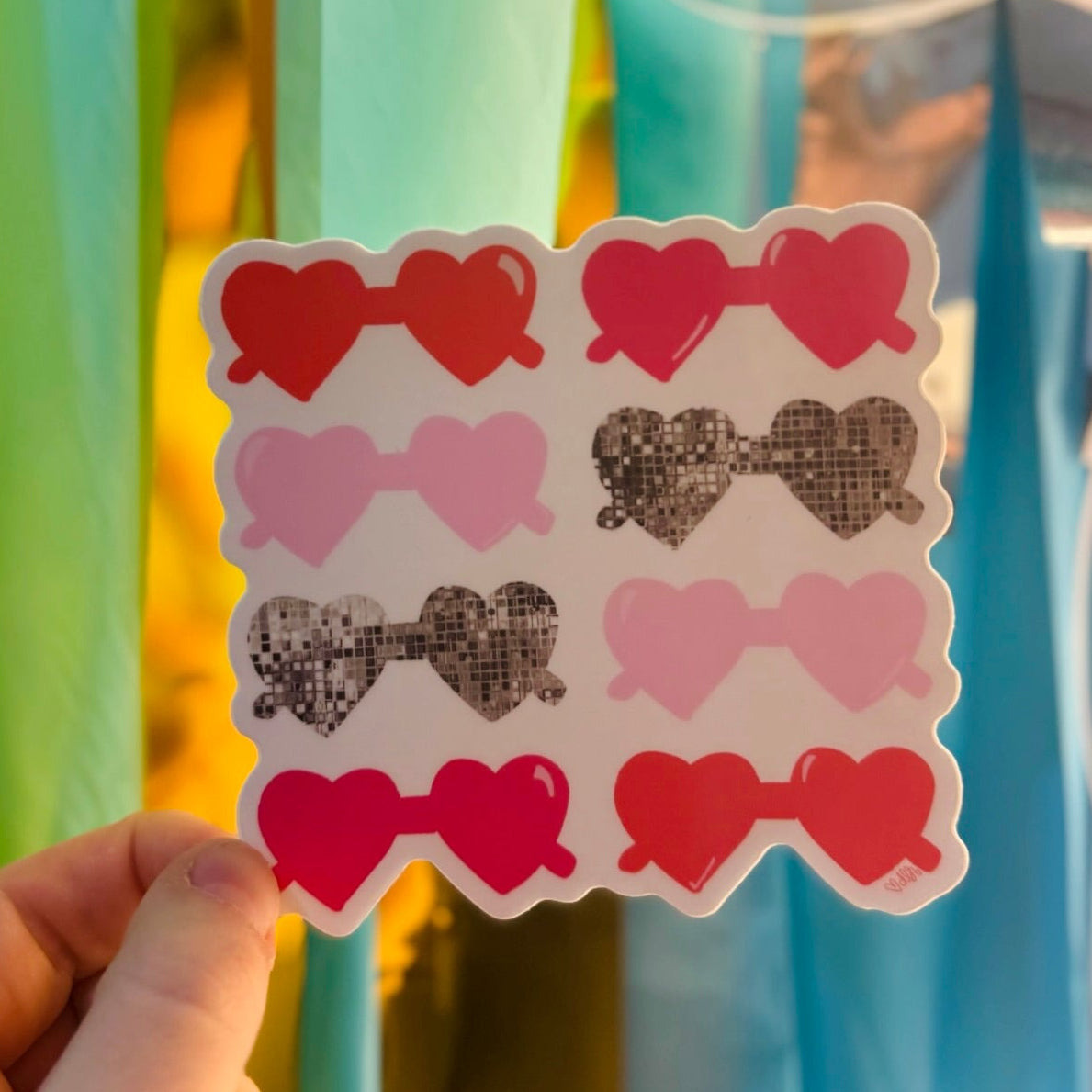 Doodles by Rebekah heart-shaped sunglasses sticker. This whimsical vinyl decal features a mix of pink, red, and disco ball heart glasses, making it an ideal gift for fans of pop culture and retro style to decorate water bottles, laptops, and planners.