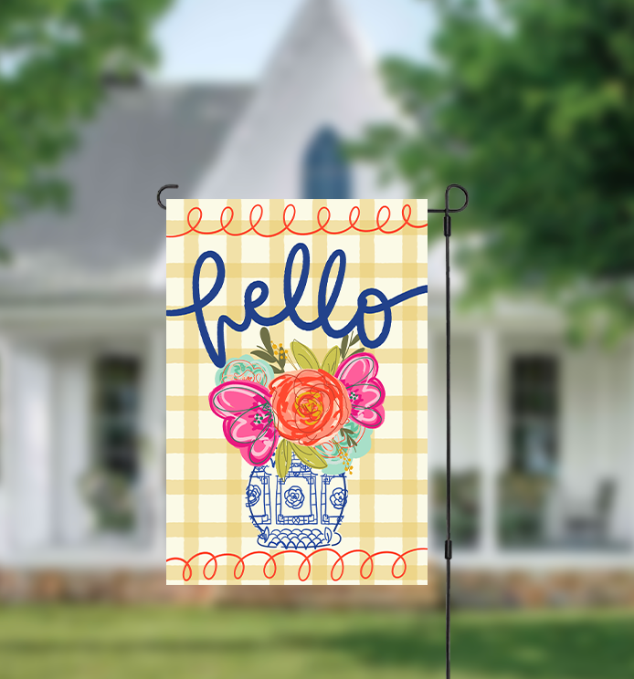 Decorative garden flag with floral design and 'hello' text in front of a house.