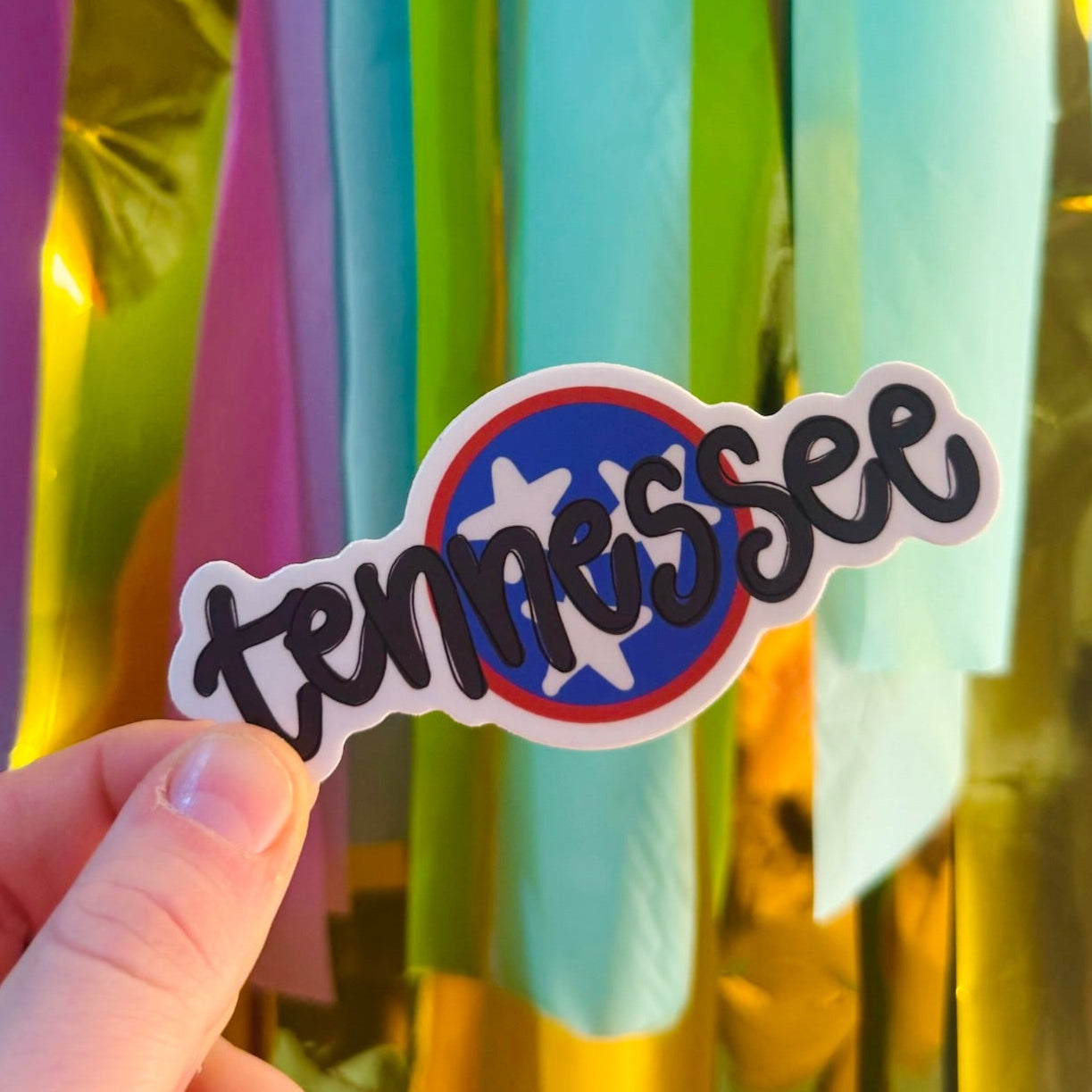 Doodles by Rebekah Tennessee state tristar pride sticker. This whimsical hand-painted vinyl decal with bold black typography and a state flag emblem is a perfect gift for Tennesseans to decorate water bottles, laptops, and planners.