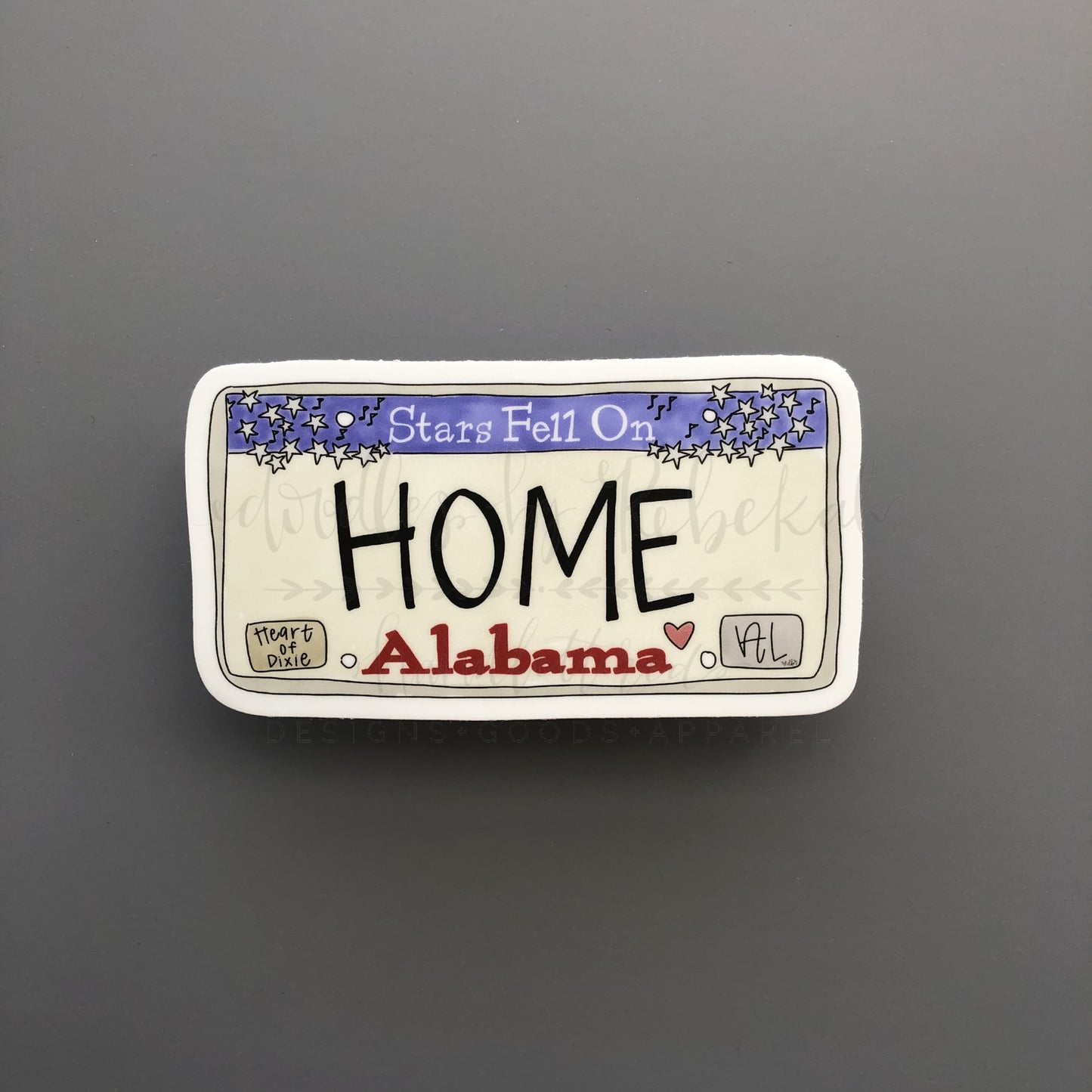a grey background with a sticker of an Alabama license plate that reads "Home"