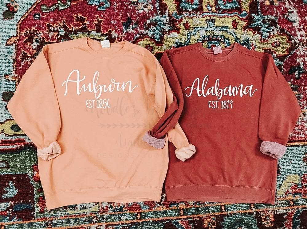 Two Sweatshirts against a multicolored background, one Auburn, one Alabama, showing year the college was established