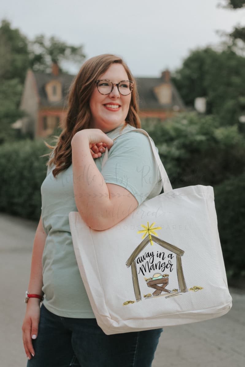 Woman holding a white tote bag with a manger scene