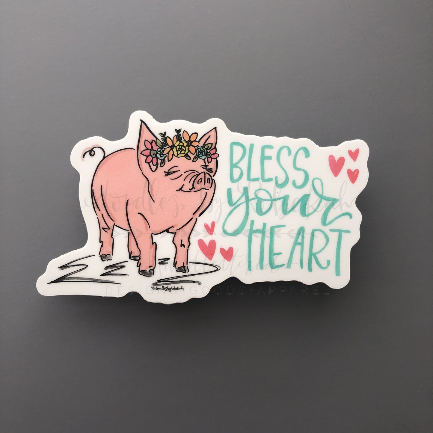 A sticker with an illustration of a pig and the phrase 'Bless your heart' surrounded by hearts.