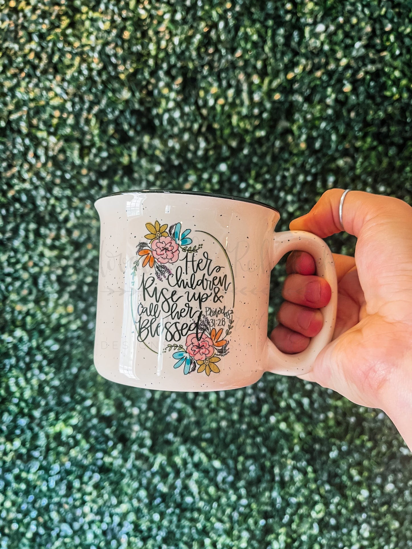 A white speckled mug with Proverbs 31:28 scripture on it