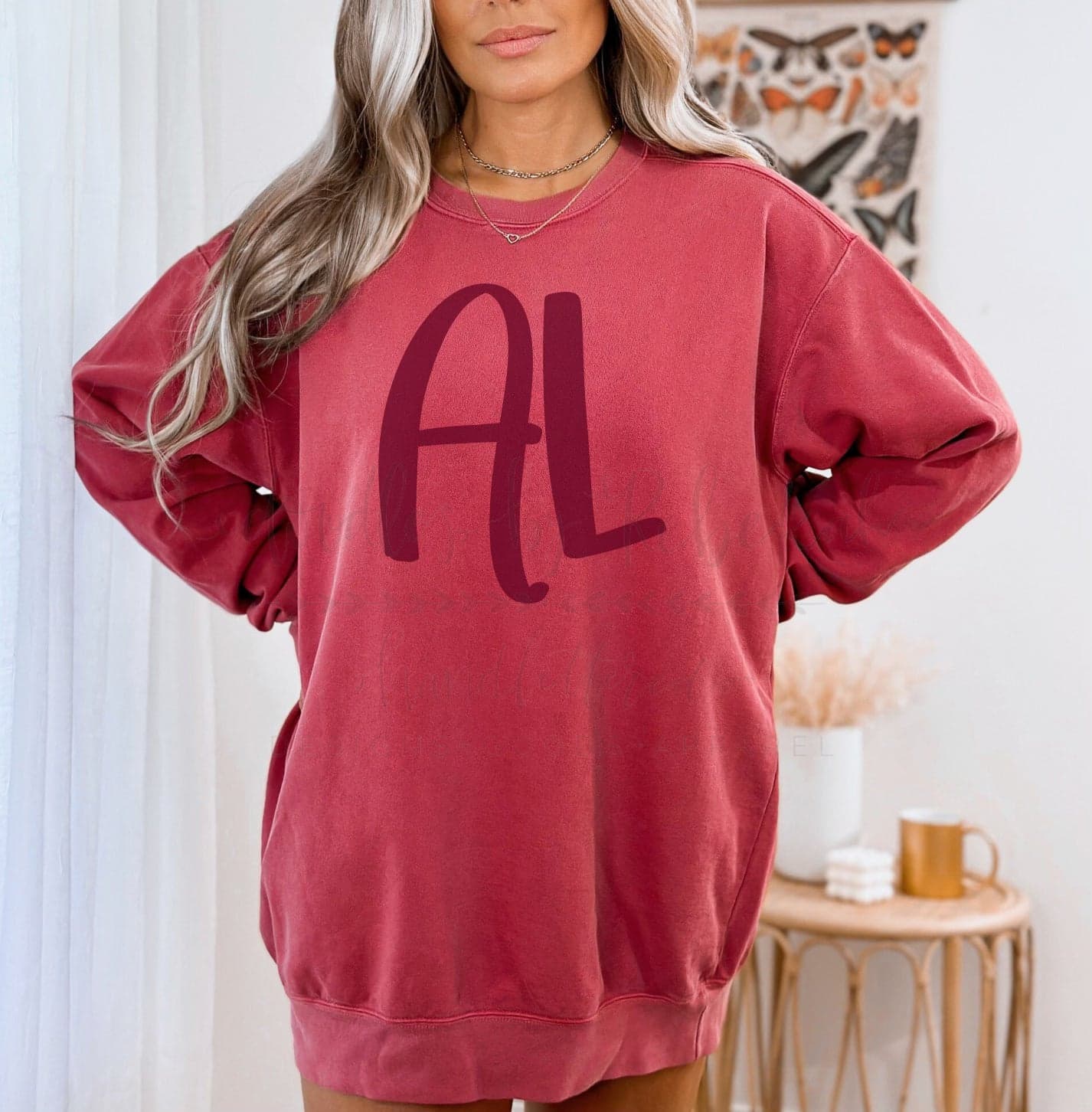A person wearing a red long-sleeved sweatshirt with the letter 'AL' printed in the center.