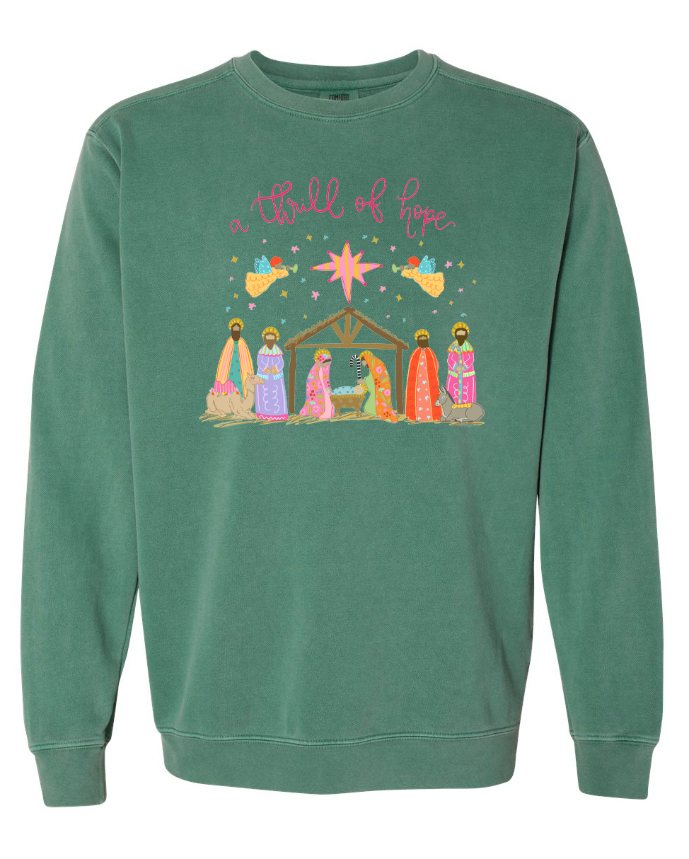Green sweatshirt with nativity scene design and 'a thrill of hope' text on a white background