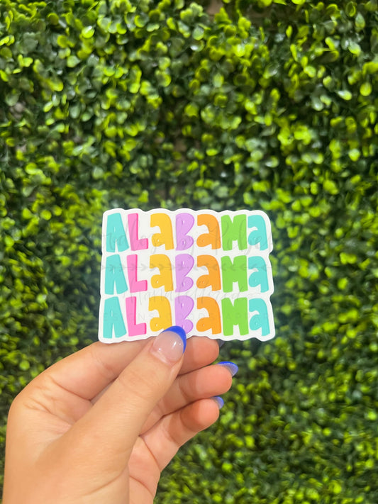 Someone holding a colorful sticker that spells out ALABAMA