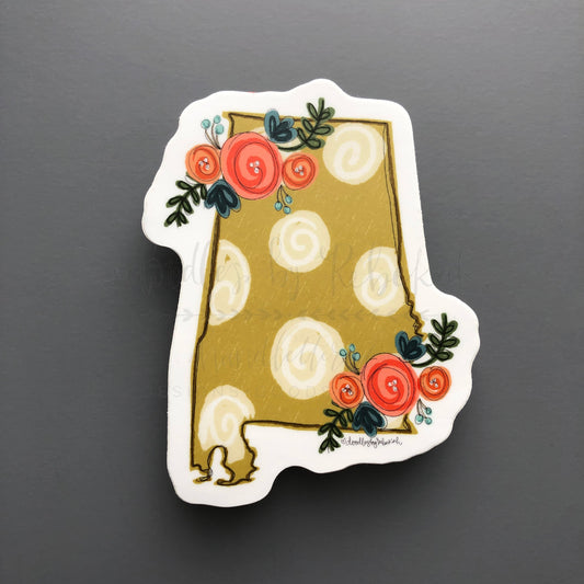 A sticker with a gold background and a floral pattern consisting of red and blue flowers and green leaves on a white-backed dot design.