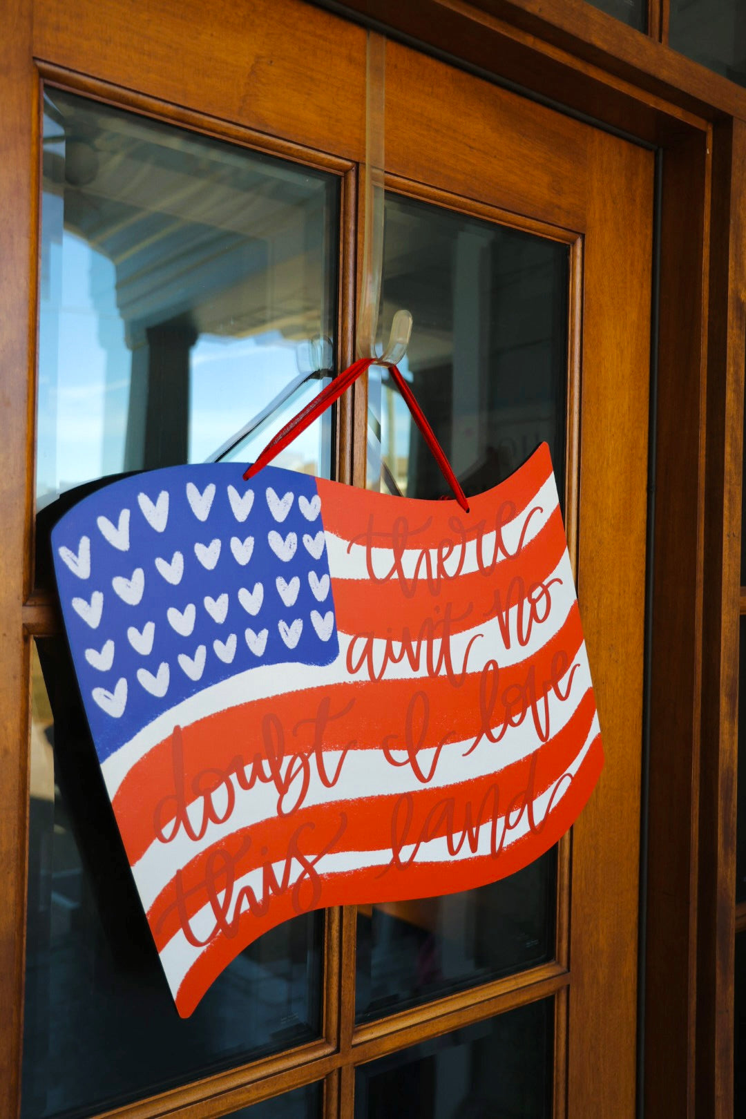 A door hanger with a design resembling the American flag with white hearts on the blue field, displayed on a wooden door.