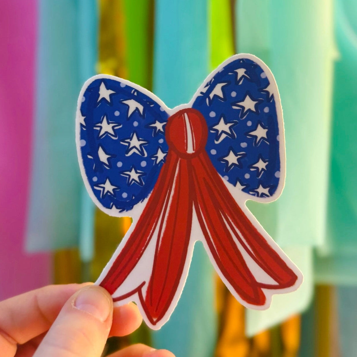 Doodles by Rebekah patriotic American flag bow sticker. This whimsical hand-painted red, white, and blue vinyl decal is a perfect accessory for Fourth of July decorating, or for personalizing water bottles, laptops, and coolers.