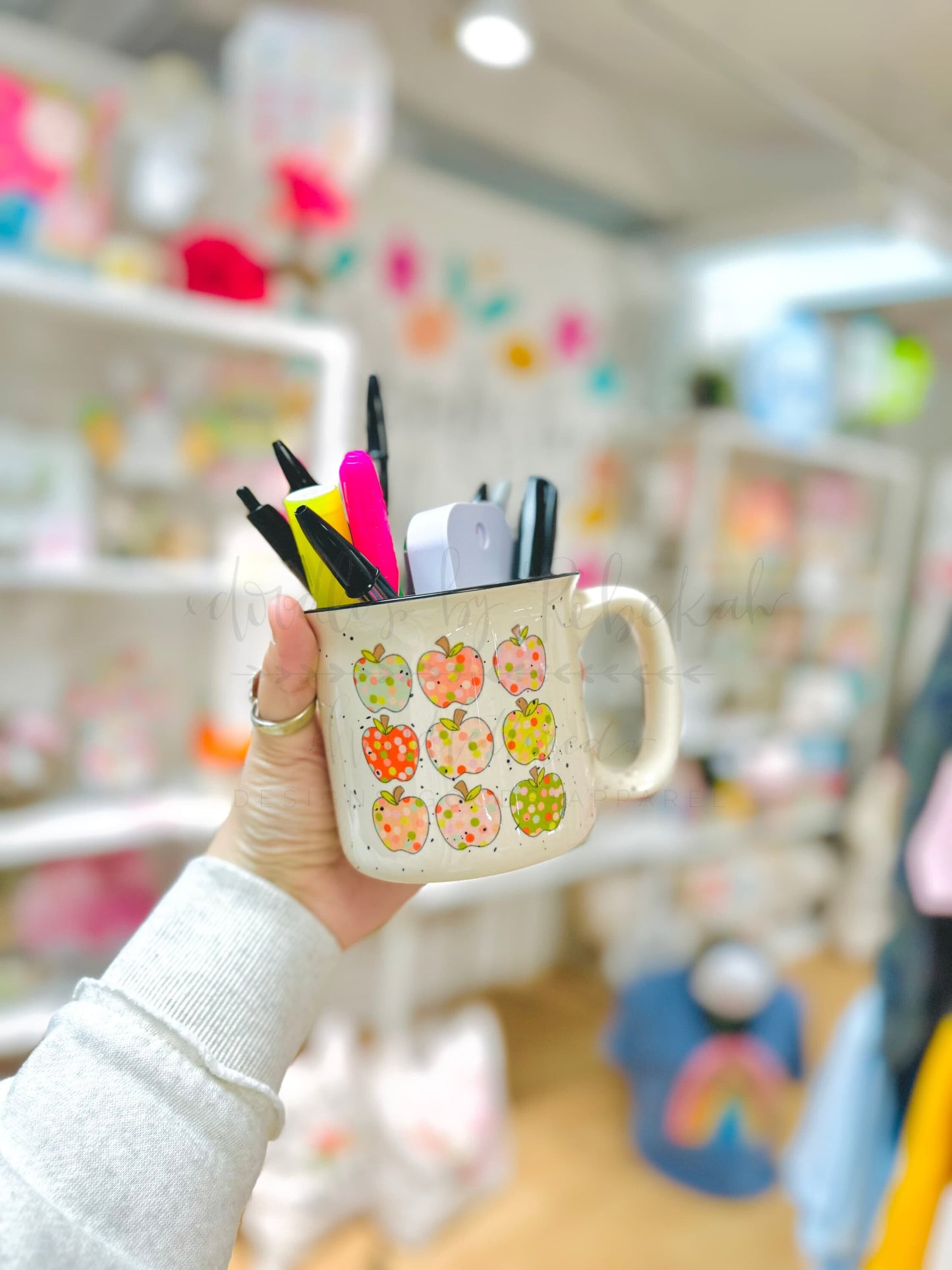 Person holding a coffee mug with apples on it