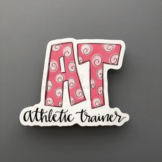 A pink sticker with the word 'ATHLETIC TRAINER' written in bold letters, surrounded by a swirl pattern.