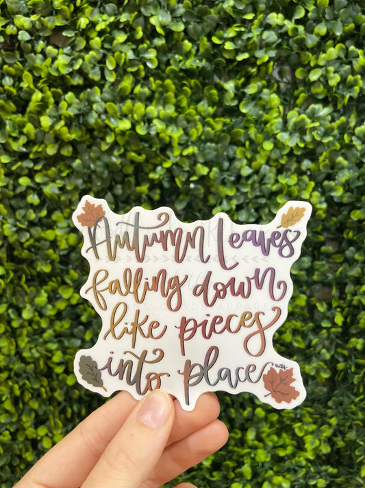 A sticker with a fall-themed design, featuring text that reads 'Autumn leaves falling down like pieces into place', surrounded by leaf illustrations in purple and gold colors.