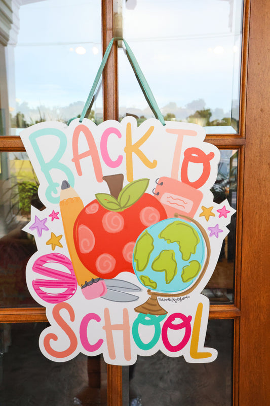Decorative sign with 'Back to School' text and school-themed graphics on a glass door.