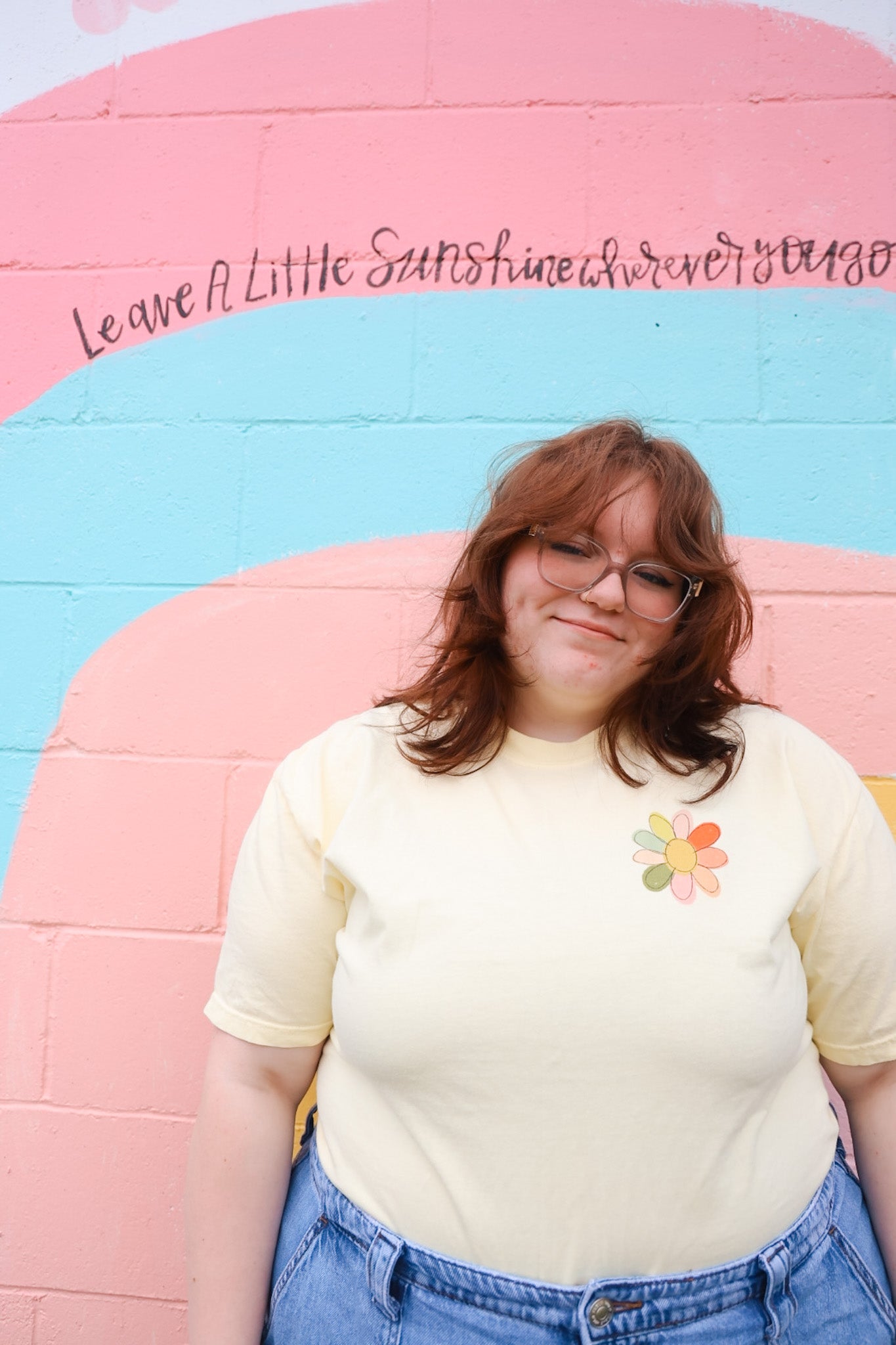 Person wearing a yellow t-shirt with a small flower on left top