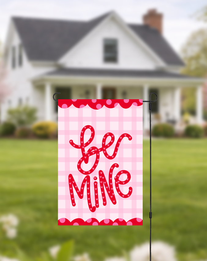 Doodles by Rebekah "Be Mine" Valentine's Day garden flag featuring whimsical hand-painted typography and a pink checkered pattern. This romantic outdoor holiday decor is perfect for Valentine's Day celebrations or adding a festive touch to front yard landscaping.