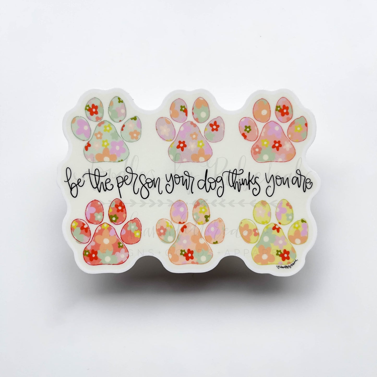 Vinyl sticker with paw prints and a floral graphic with the phrase "be the person your dog thinks you are"