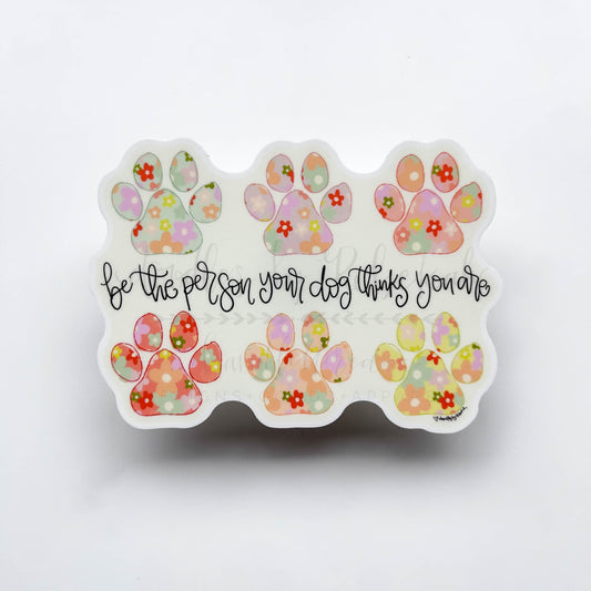 Vinyl sticker with paw prints and a floral graphic with the phrase "be the person your dog thinks you are"