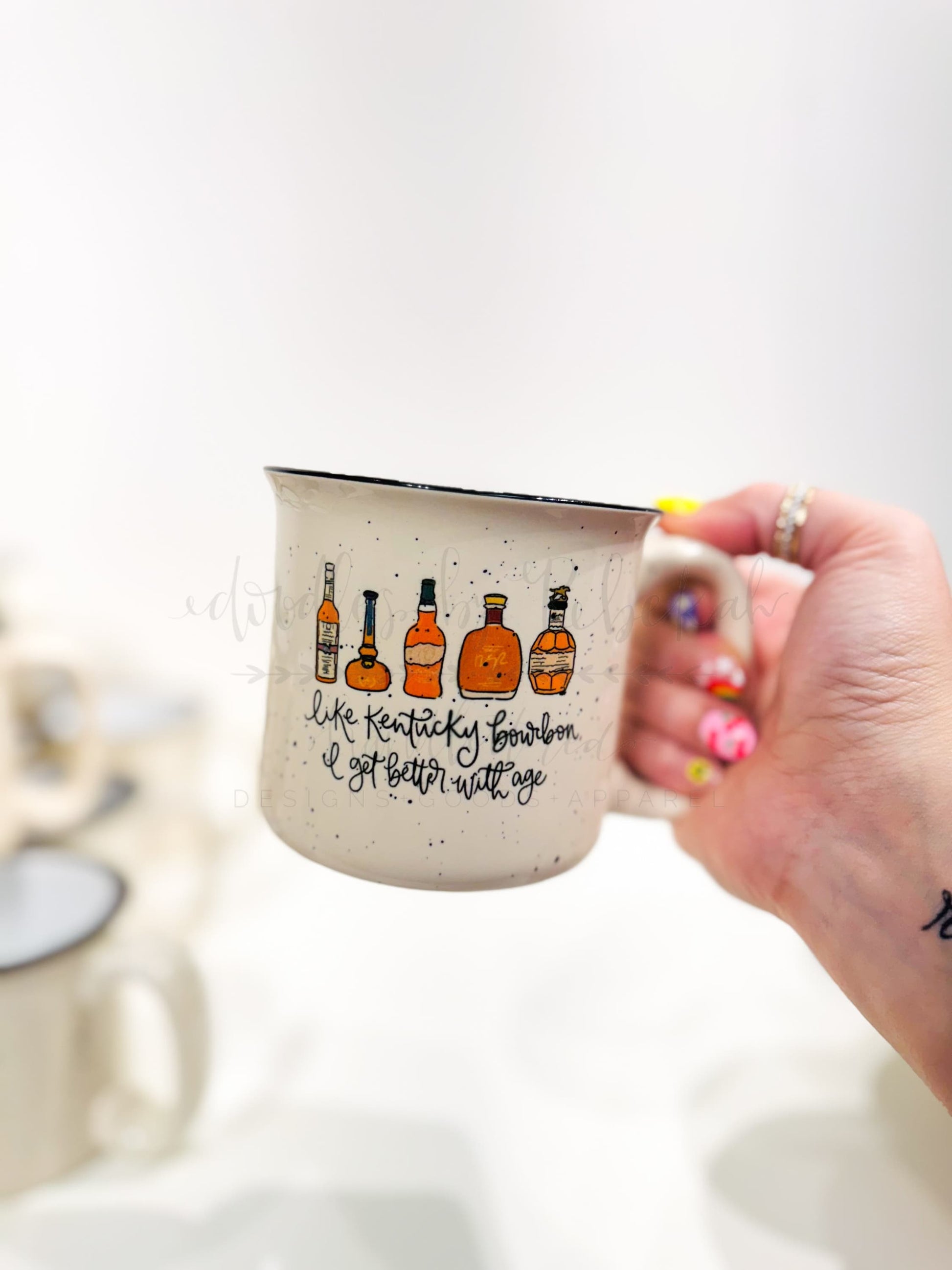 Kentucky bourbon campfire mug with whimsical bottle graphics and "better with age" calligraphy, an ideal gift for bourbon lovers and birthdays.