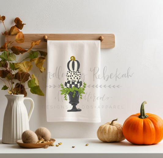 Whimsical fall tea towel with a black and white patterned pumpkin topiary illustration, perfect for autumn kitchen decor and Thanksgiving hosting gifts.