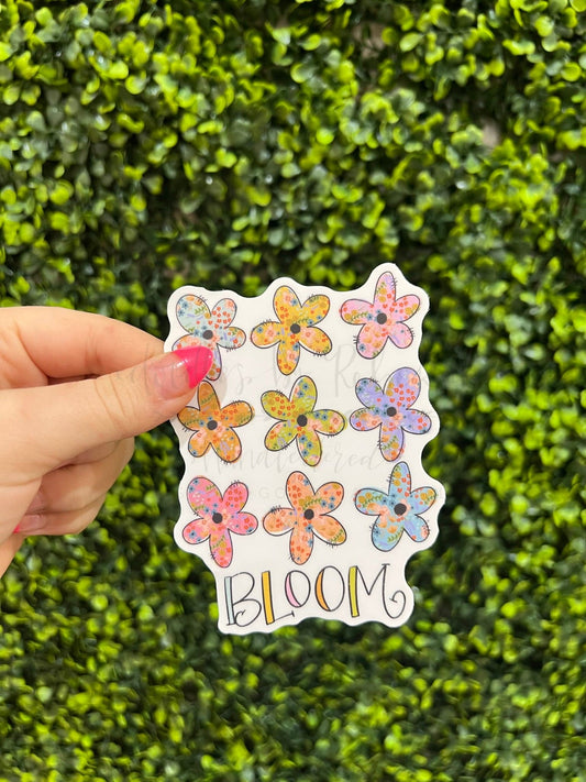 Colorful sticker with nine daisies drawn over the text "Bloom"