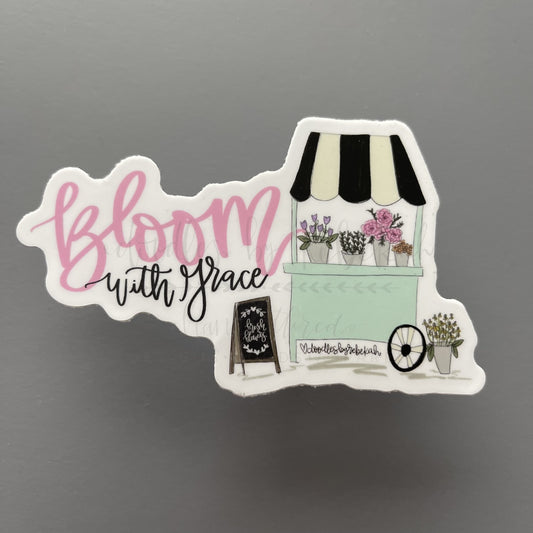 A sticker with a floral design and the text 'Bloom with Grace' from a store front window scenario, indicating it is meant for decorating devices or surfaces.