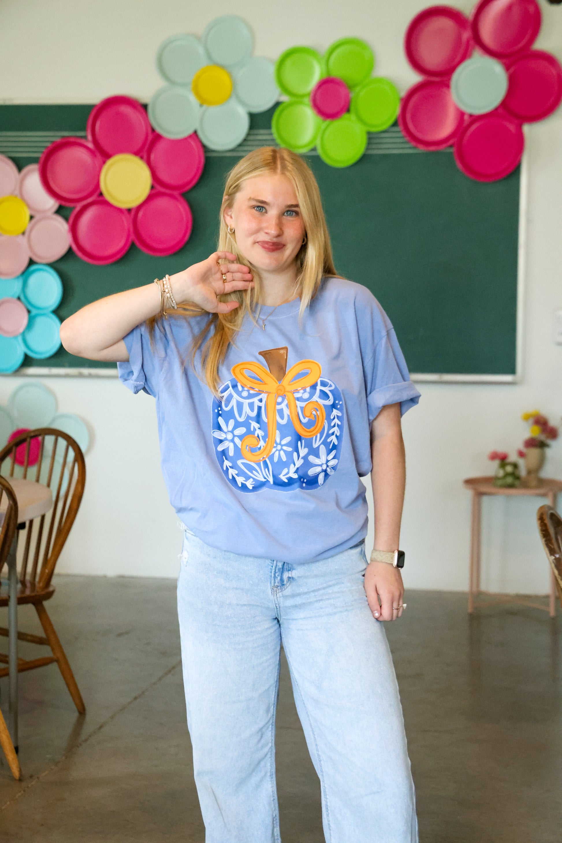 Person wearing a light blue t-shirt with a colorful design in a classroom setting