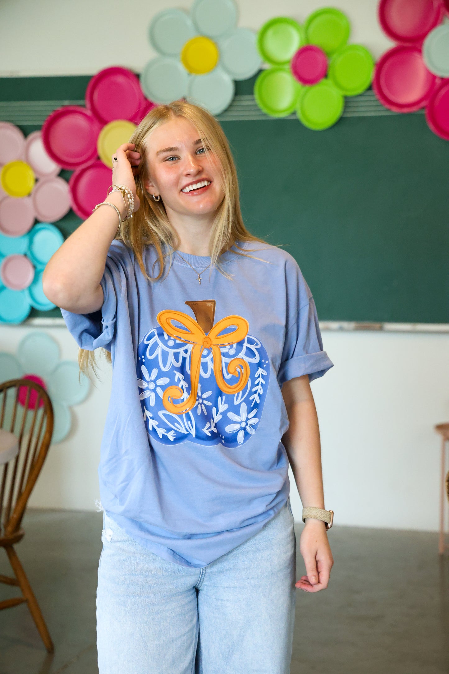 Person wearing a blue t-shirt with a colorful design in a classroom setting