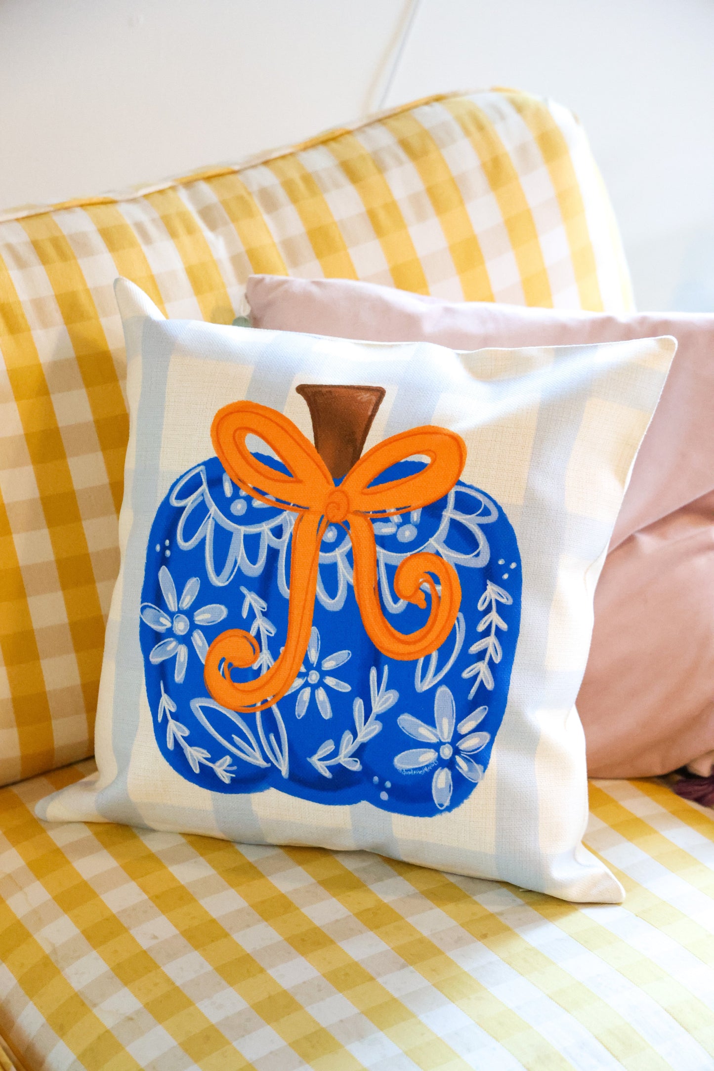Decorative pillow with a blue and orange design on a yellow checkered couch.