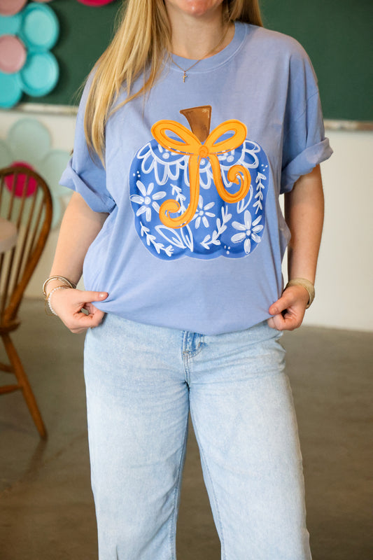 Person wearing a light blue t-shirt with a decorative design, standing indoors.