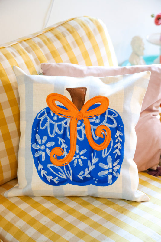 Decorative pillow with a blue and orange design on a yellow checkered couch.