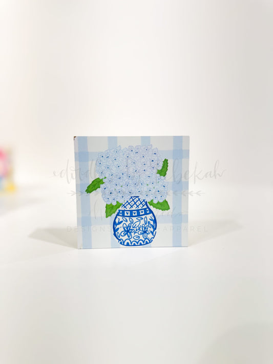 A decorative 4x4 block with a blue hydrangea design on a white background, placed against a plain background.