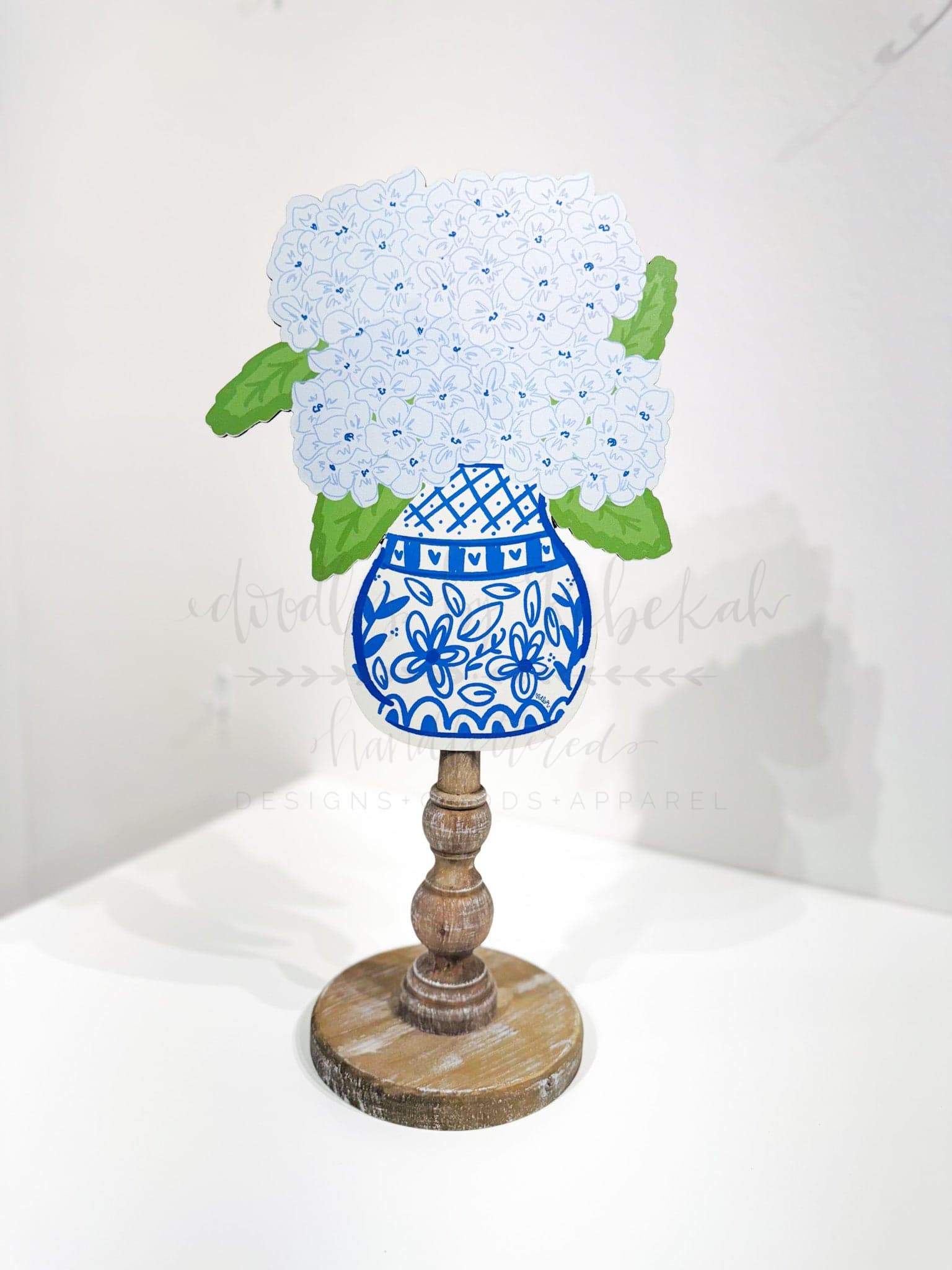 A decorative blue hydrangea topper made of MDF, with a white dotted pattern and green leaves, displayed on a wooden stand.