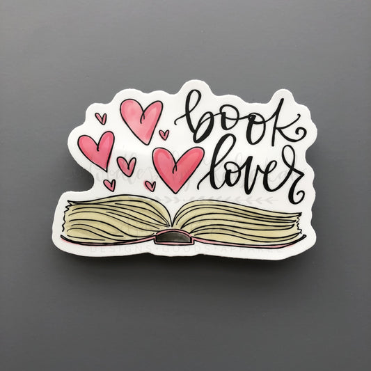 A white sticker with an open book and hearts that reads "book lover"