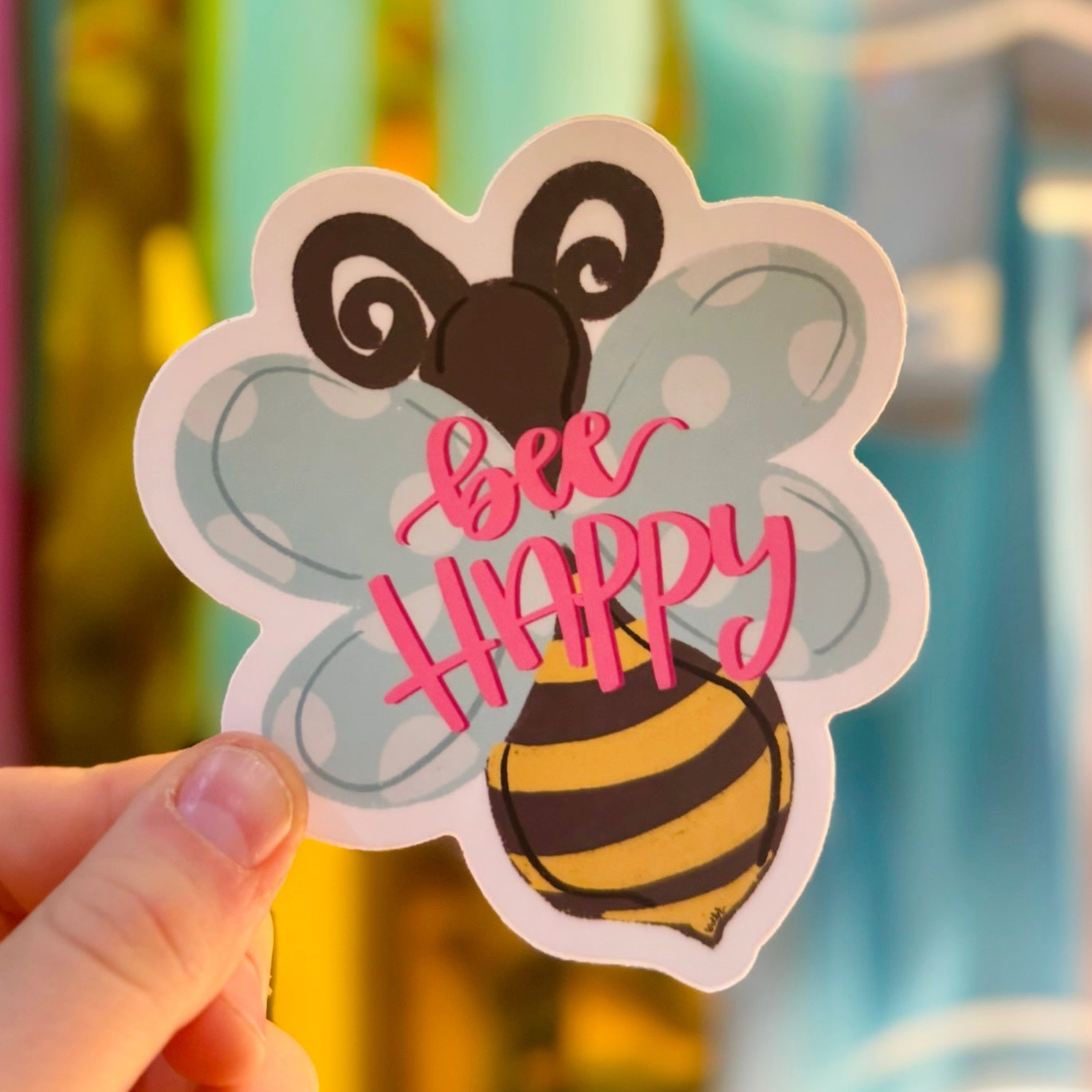 Doodles by Rebekah "Bee Happy" inspirational honeybee sticker. This colorful hand-painted vinyl decal with a polka-dot wing bee and pink typography is a perfect motivational gift for decorating water bottles, laptops, and planners.