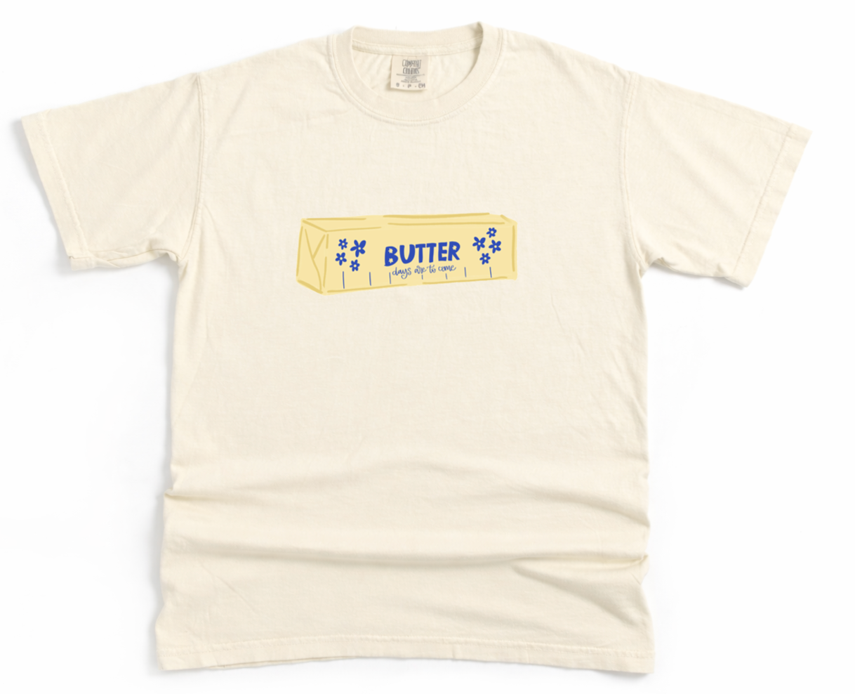Beige t-shirt with a graphic of a butter container on a white background