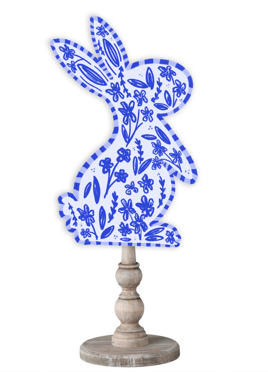Doodles by Rebekah Easter bunny decor featuring a whimsical blue floral pattern and striped border on a rustic wood stand.