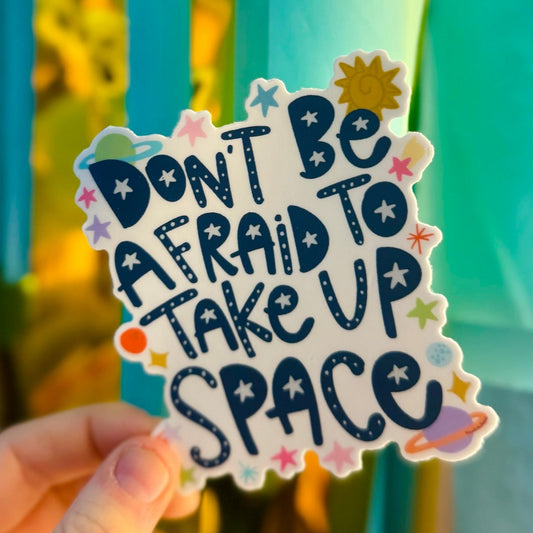Doodles by Rebekah "Don't Be Afraid to Take Up Space" celestial-themed inspirational sticker. This whimsical hand-painted vinyl decal with sun, stars, and planet accents is a perfect motivational gift for decorating water bottles, laptops, and telescopes.