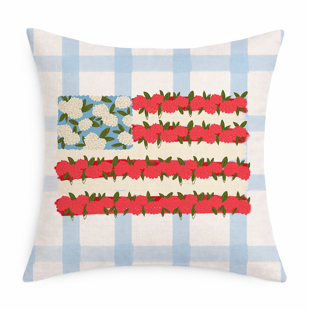 A blue and white gingham pillow with a floral American flag on it on a white background