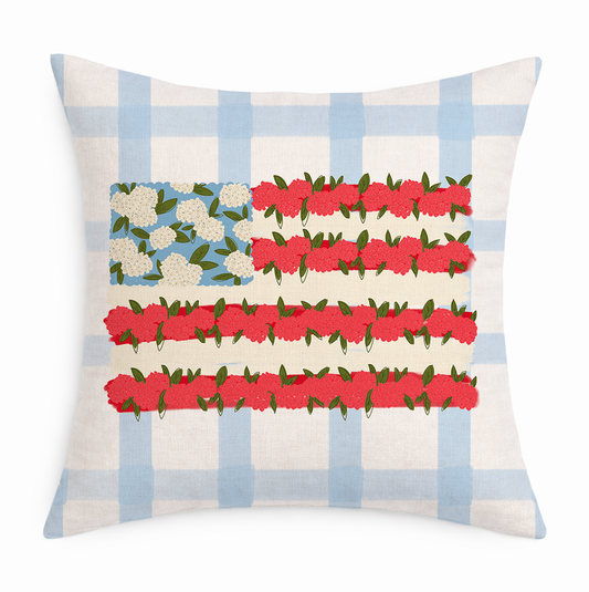 A blue and white gingham pillow with a floral American flag on it on a white background