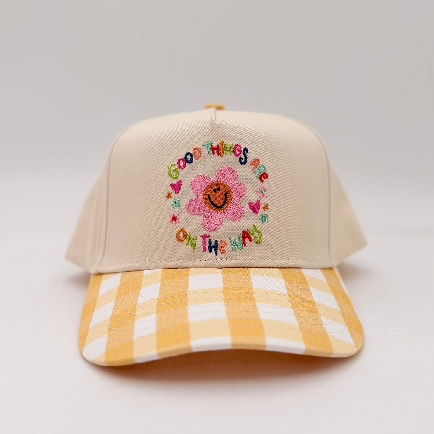 Beige cap with floral design and text on a light gray background