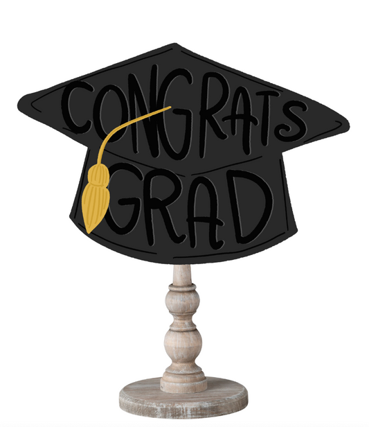 Doodles by Rebekah graduation gift decor featuring a whimsical hand-sketched mortarboard and tassel on a rustic wooden stand.
