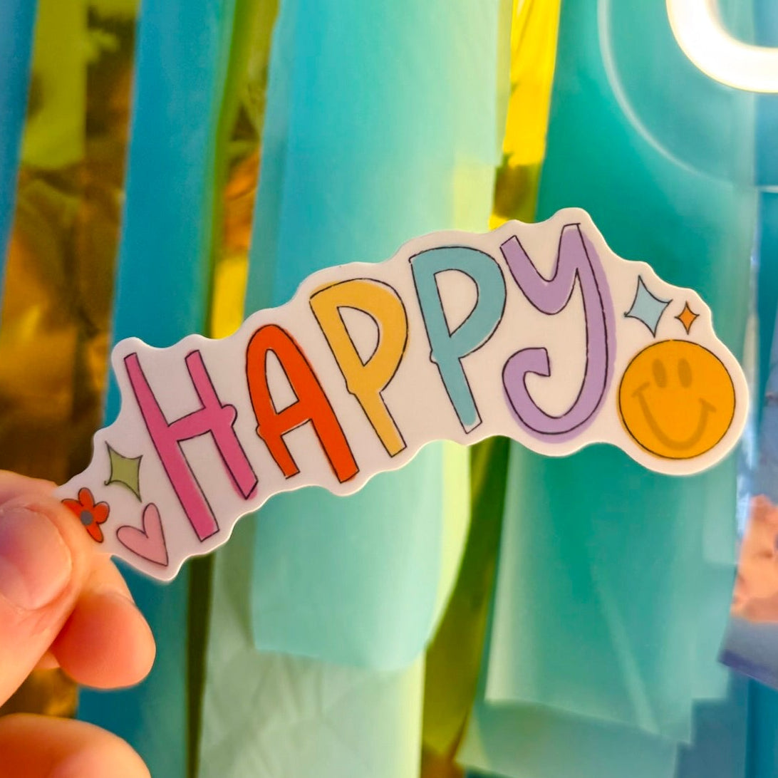 Doodles by Rebekah "HAPPY" multi-colored typography sticker. This whimsical hand-painted vinyl decal with a smiley face and heart accents is a perfect gift for spreading joy on water bottles, laptops, and planners.