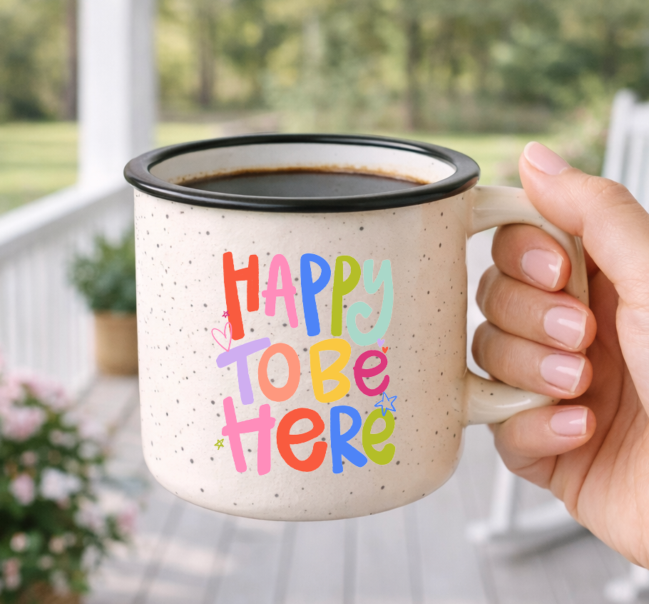 Doodles by Rebekah "Happy To Be Here" inspirational campfire mug. This whimsical hand-painted ceramic coffee cup features vibrant typography and is an ideal gift for positive home decor, daily encouragement, or as a cheerful addition to a farmhouse-style kitchen.